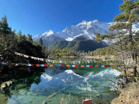Beautiful mountain reflection in an alpine lake with colorful prayer flags along the Annapurna Circuit trek.