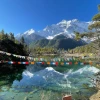 Beautiful mountain reflection in an alpine lake with colorful prayer flags along the Annapurna Circuit trek.