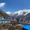 Scenic view of Langtang village beneath towering snow-covered mountains and bright blue skies in Nepal.