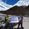 Two trekkers holding a Manaslu Circuit Trek banner at Larke La Pass (5106m)